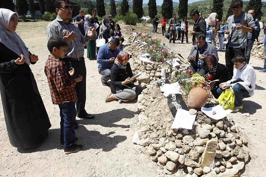 People mourn at graves for miners who died in Tuesday's mine disaster, at a cemetery in Soma, a district in Turkey's western province of Manisa on May 18, 2014. -- PHOTO: REUTERS