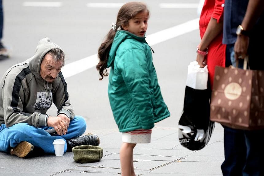 This photo taken on May 12, 2014 shows a homeless man sitting on a street in Sydney.&nbsp;Australian Prime Minister Tony Abbott has suffered a voter backlash after a budget described as the worst in 20 years with two polls Monday showing support for 