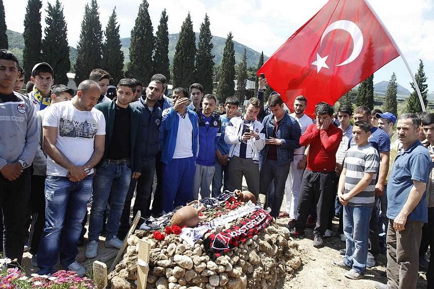 People mourn at graves for miners who died in Tuesday's mine disaster, at a cemetery in Soma, a district in Turkey's western province of Manisa on May 18, 2014.&nbsp;Two more officials in Turkey have been charged with manslaughter as the government p