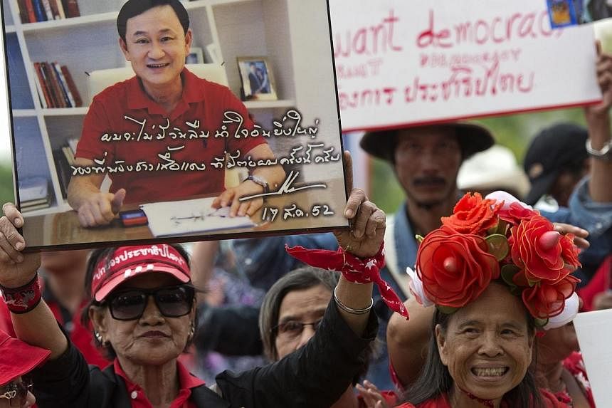 Thai pro-government "Red Shirts" holds a portrait of fugitive former premier Thaksin Shinawatra during a rally at Phutthamonthon suburb of Bangkok on April 5, 2014.&nbsp;Thailand's ousted prime minister Thaksin Shinawatra, a hugely controversial figu