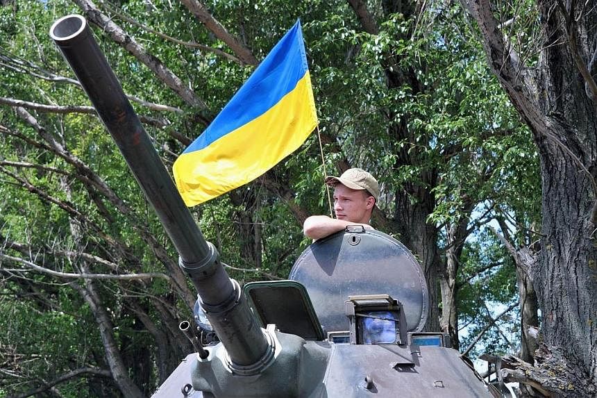 A Ukrainian soldier stands guard on an armoured personnel carrier on the road from Izyum to Slavyansk on May 20, 2014.&nbsp;Ukraine confirmed on Tuesday, May 20, 2014, that Russia had pulled its troops back from the border for the first time in a mov