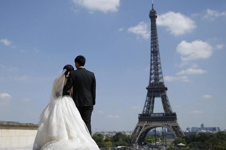 A wedding couple of tourists pose for their own photographer at the Trocadero Square near the Eiffel Tower in Paris on May 16, 2014. People tend to choose spouses who have similar DNA, according to scientists who reported on Monday, May 19, 2014, the