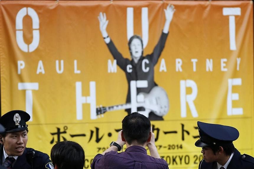 A fan takes a photo of a banner of singer Paul McCartney after the cancellation of McCartney's concert at the National Stadium in Tokyo May 18, 2014.&nbsp;Former Beatle Paul McCartney has cancelled his Japan tour due to illness, organisers said on Tu
