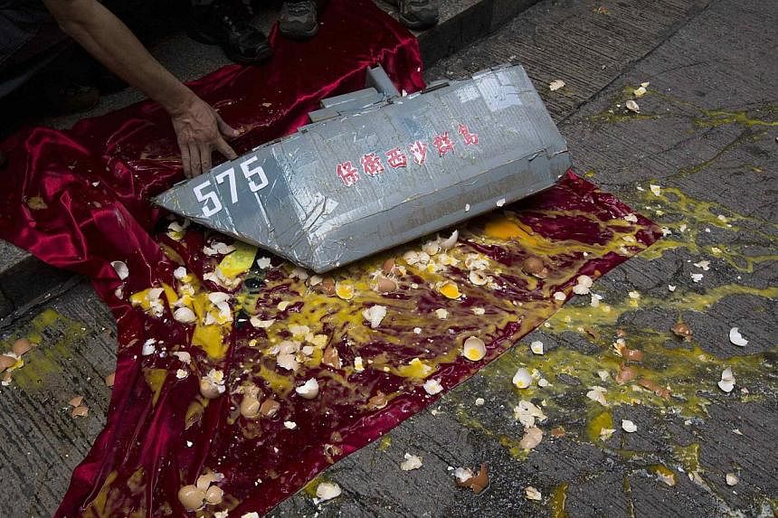 An anti-Vietnam protester picks up a model of Chinese People's Liberation Army Navy (PLAN) Type 054A Frigate FFG-575 Yueyang on a Vietnamese flag, as eggs are thrown by anti-Vietnam protesters, during a protest defending China's territory claim and c