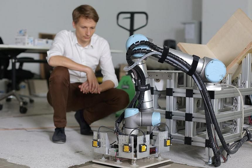 Tobias Bonwetsch, a team member that worked on the prototype, looks on as he gives demonstrates the capabilities of the robotic tiling machine. -- ST FILE PHOTO: ONG WEE JIN