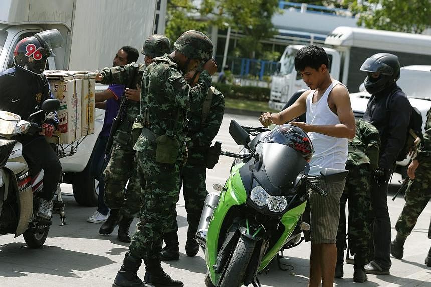 Thai armed soldiers make security checks at checkpoint near a pro-government Red Shirt supporters rally site on the outskirts of Bangkok, Thailand on May 20, 2014. -- PHOTO: EPA