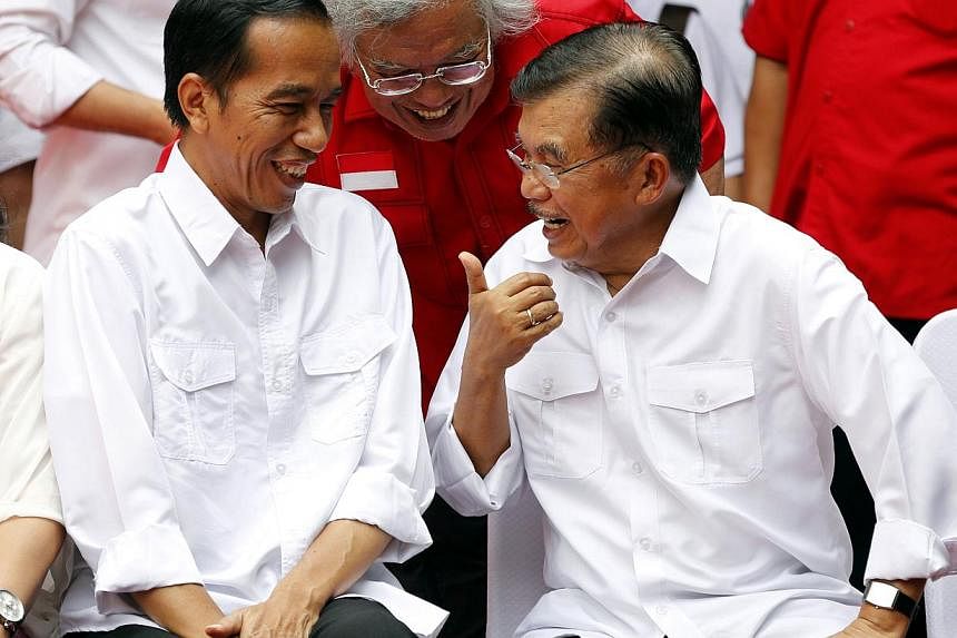 Indonesian presidential candidate Joko "Jokowi" Widodo (L) chats with his vice presidential running mate Jusuf Kalla (R) during an event declaring their bid in the upcoming July 9 election, in Jakarta May 19, 2014. Jokowi received a major boost in th