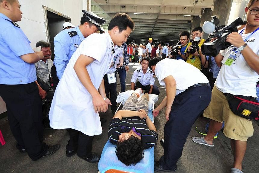 An injured man (centre) is helped on to a stretcher by medical personnel after leaving the "Wuzhishan" passenger boat that arrived at a port, after picking up Chinese citizens from Vietnam, in Haikou, Hainan province May 20, 2014. -- PHOTO: REUTERS &