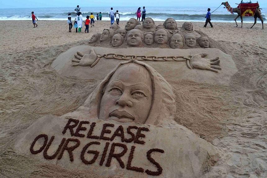Indian beachgoers pass a sand sculpture, calling for the release of kidnapped school girls in Nigeria, which has been created by sand artist Sudarsan Pattnaik on the beach in Puri, some 65 kms from Bhubaneswar on May 10, 2014. -- FILE PHOTO: AFP