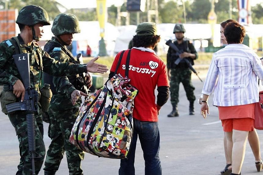 Thai soldiers inspect the bag of a member of the pro-government "red shirt" group at an encampment in Nakhon Pathom province on the outskirts of Bangkok on May 22, 2014.&nbsp;Thailand's army told all television and radio stations in the country to ha
