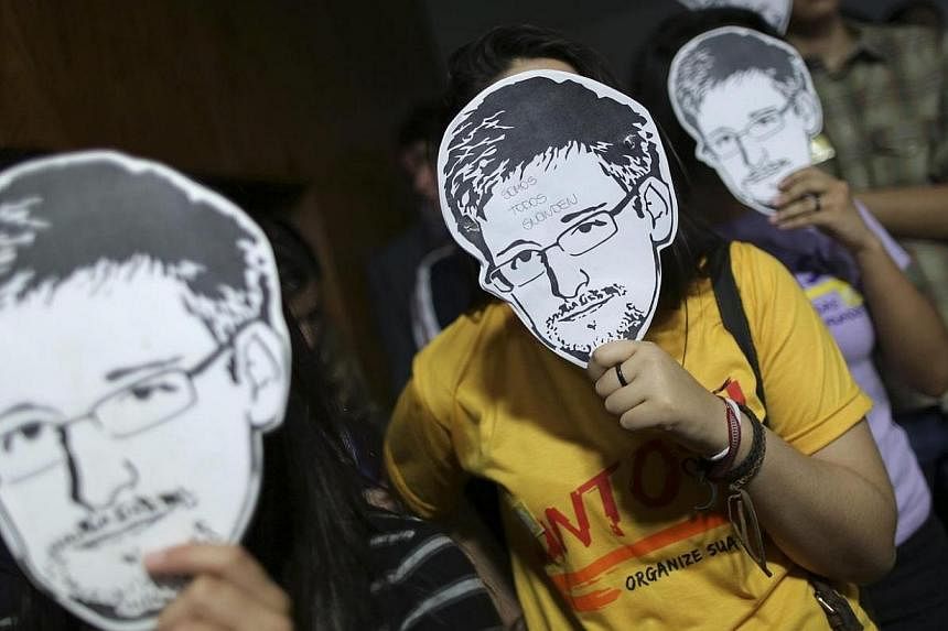 People holds masks with pictures of former NSA contractor Edward Snowden during the testimonial of Glenn Greenwald, the American journalist who first published the documents leaked by Snowden, in Brasilia on August 6, 2013.&nbsp;The House of Represen