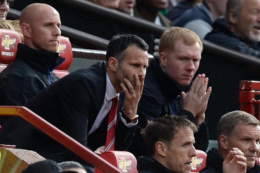 Manchester United legend Paul Scholes (seen here assisting interim manager Ryan Giggs last season) has said in a blog post he does not expect to return to Old Trafford as part of new coach Louis van Gaal's set-up for the new season. -- PHOTO: AFP