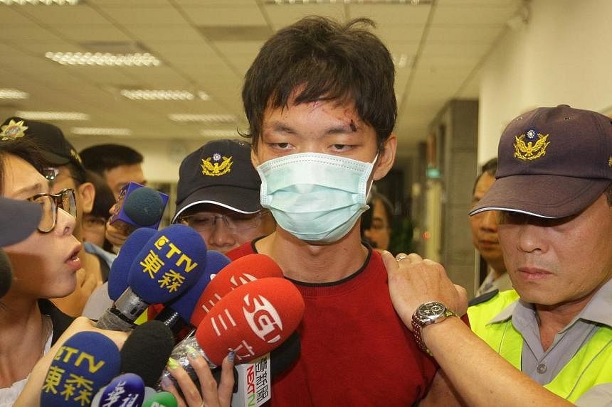 The alleged attacker Cheng Chieh (centre) is transferred by policemen at a local police station in New Taipei City on May 22, 2014. -- PHOTO: AFP