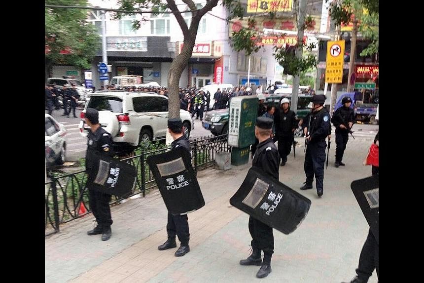 Riot policemen look behind them toward the site of an explosion, which has been cordoned off, as they stand guard in downtown Urumqi, Xinjiang Uighur Autonomous Region on May 22, 2014, in this photo distributed by China's official Xinhua News Agency.