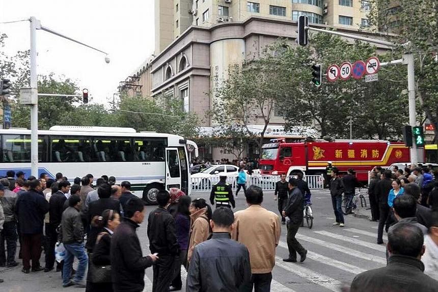Residents gather to watch as police seal off the site where attackers ploughed two vehicles into a market and threw explosives, killing at least 31 people, in Urumqi in northwest China's Xinjiang region on May 22, 2014. -- PHOTO: AFP