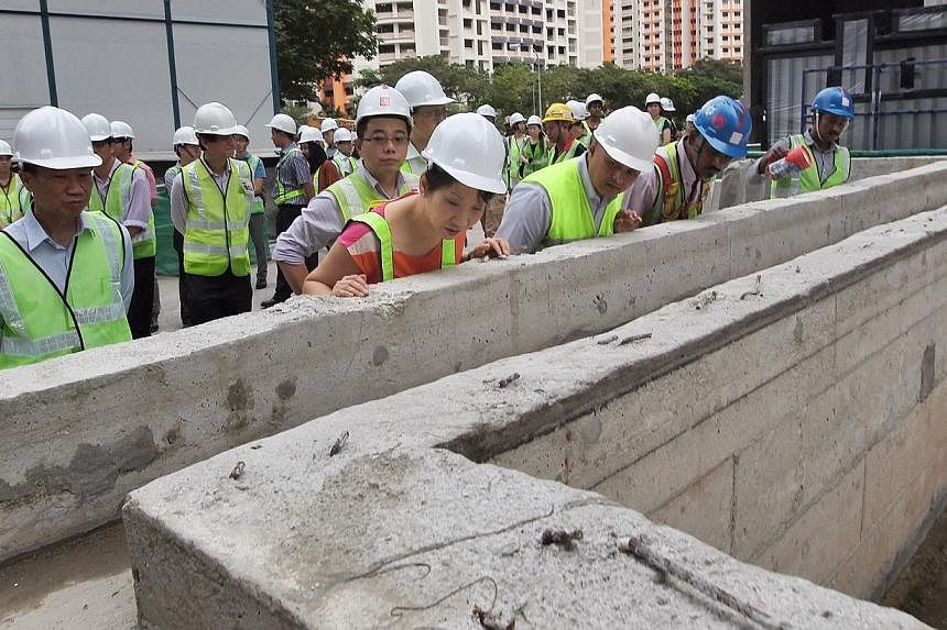 Second Minister for the Environment and Water Resources Grace Fu (in orange) checks out a possible stagnant water area at the future swimming pool of The Luxurie at Compassvale (Sengkang) construction site. She was there to observe the housekeeping r