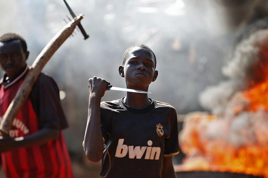 A boy gestures in front of a barricade on fire during a protest after French troops opened fire at protesters blocking a road in Bambari on May 22, 2014. -- PHOTO: REUTERS