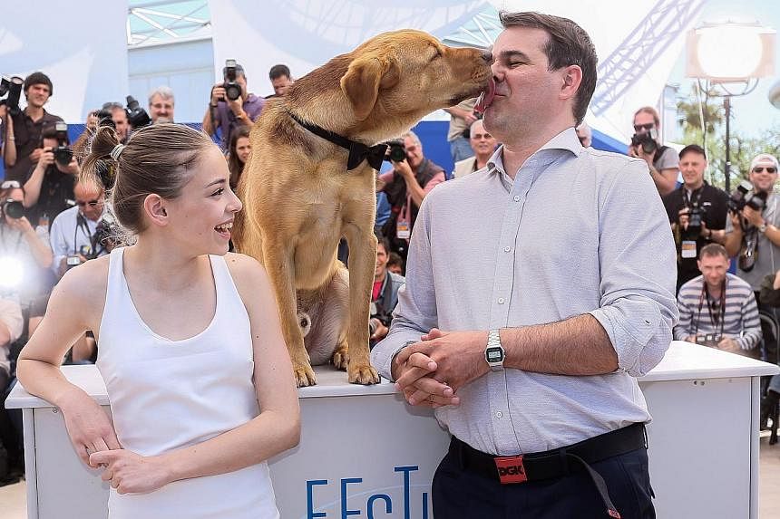 (From left) Actress Zsofia Psotta, Hagen the dog, and White God director Kornel Mundruczo posing for photographers at the Cannes Film Festival on May 17, 2014. -- PHOTO: EPA