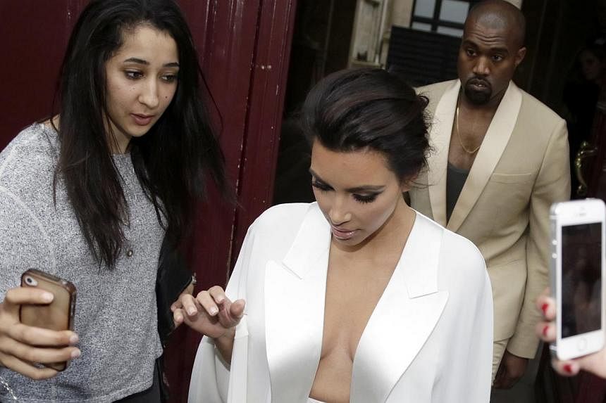 American reality TV star Kim Kardashian (centre) and American singer Kanye West (right) leave their residence in Paris on May 23, 2014, ahead of their wedding. West and his bride-to-be lunched on May 23 at a French chateau owned by iconic designer Va
