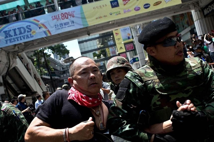 Thai soldiers take away an alleged Red-Shirt protester ahead of a planned gathering in Bangkok on May 25, 2014. Thailand's military junta said it had disbanded the Senate and placed all law-making authority in the hands of the army chief, dramaticall