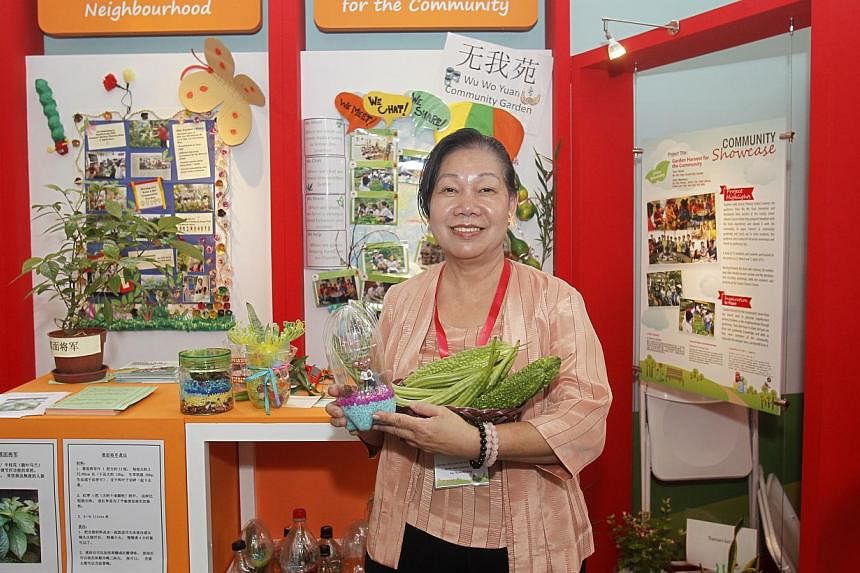 Madam Iris Chua, a 61-year-old retiree, with her neighbourhood-grown bittergourds and ladyfingers as part of a showcase of Good Neighbours Projects which promote neighbourliness in Singapore, at Toa Payoh HDB Hub Atrium on May 24, 2014. -- ST PHOTO: 