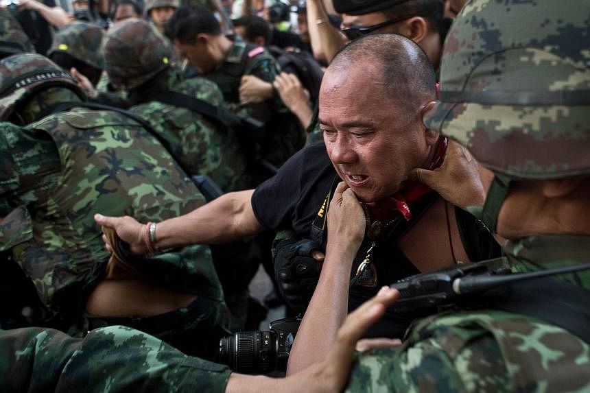 Thai army soldiers take away an alleged Red-Shirt protester ahead of a planned gathering in Bangkok on May 24, 2014. - PHOTO: AFP