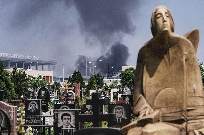 Black smoke billows from Donetsk international airport, seen behind a cemetery, during heavy gun battle between the Ukrainian army and pro-Russian militants in the eastern Ukrainian city of Donetsk on May 26, 2014.&nbsp;A fierce battle erupted on Mon