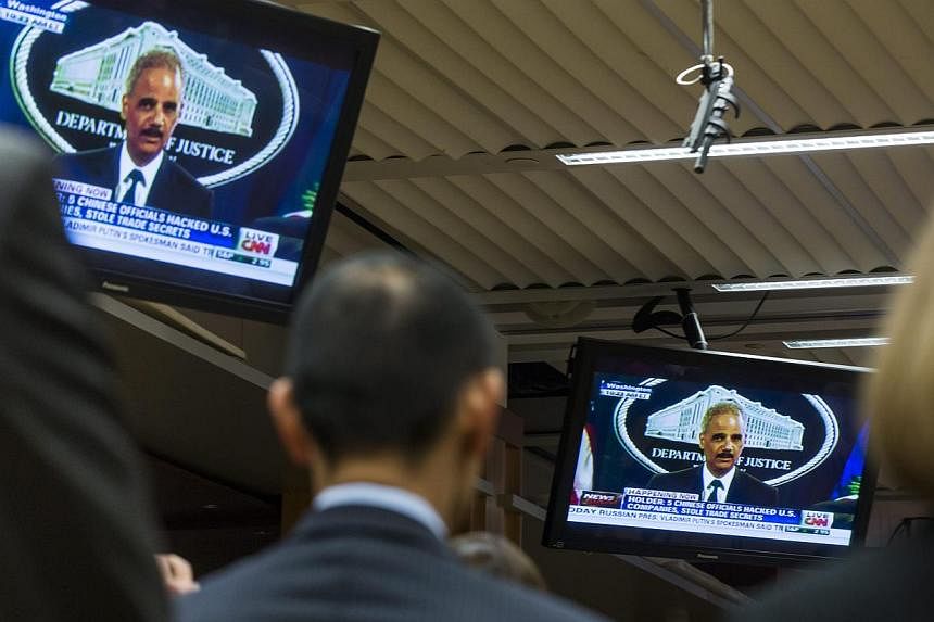 Staff members with the Department of Justice, along with reporters, watch Attorney General Eric Holder announce a federal indictment against five Chinese military officials for cyber espionage at the Justice Department in Washington on May 19, 2014. 