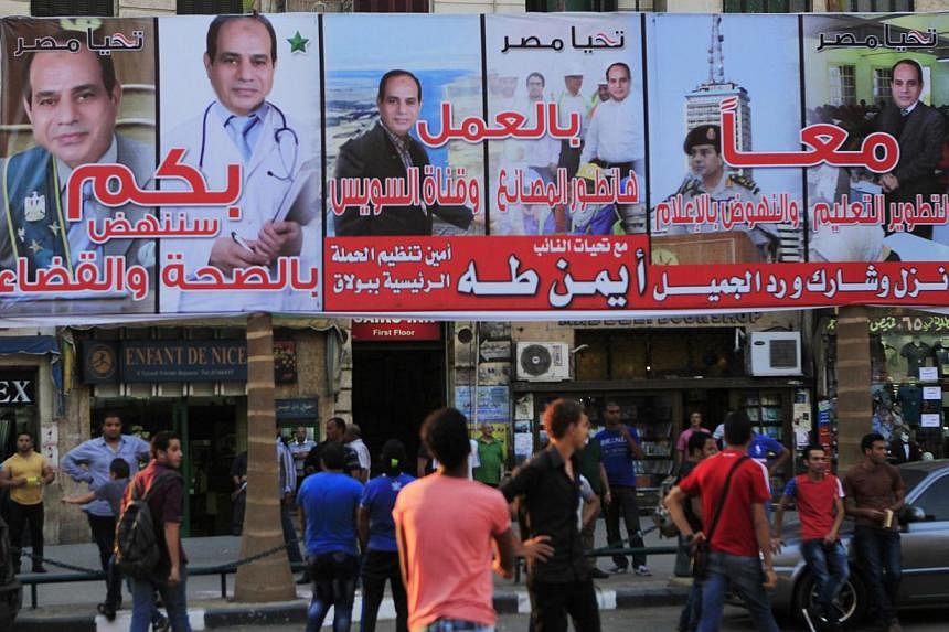 People walk under an election campaign billboard of presidential candidate and former army chief Abdel Fattah al-Sisi a day ahead of presidential elections at Talaat Harab Square in Cairo May 25, 2014. -- PHOTO: REUTERS&nbsp;