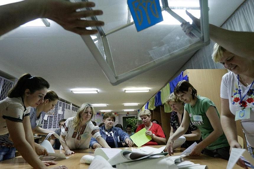 Members of the election commission empty ballot boxes in a polling station in Kiev on May 25, 2014. -- PHOTO: REUTERS