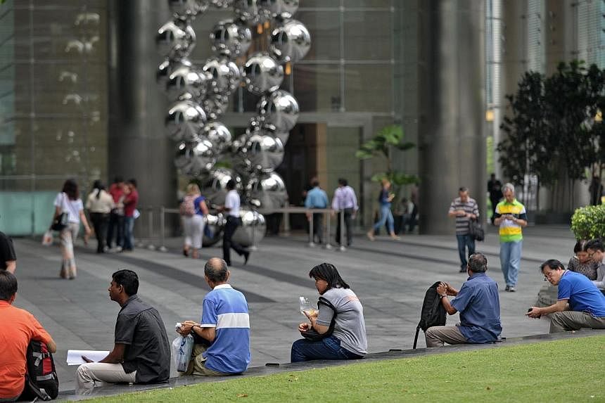 People sit along the walkway at Raffles place financial district in Singapore on April 30, 2014. Most Singaporeans do not think they will be able to retire at their desired age, according to a new survey by insurer Aviva. -- FILE PHOTO: AFP&nbsp;