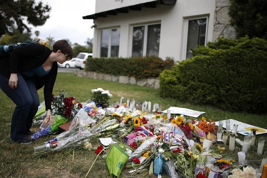 A University of California, Santa Barbara graduate student lays flowers at a makeshift memorial in front of the Alpha Phi sorority house where two women were killed. Police in the California community where a man killed six college students said they