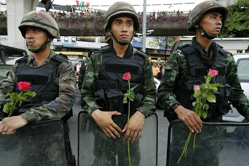 Thai armed soldiers hold flowers as they stand by as anti-coup protesters rally against the military junta at Victory Monument in Bangkok, Thailand on May 27, 2014.&nbsp;Thailand's ruling body, the National Council for Peace and Order, announced on T