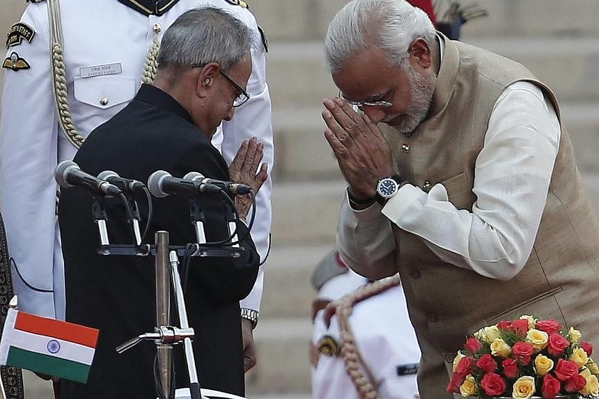 India's Prime Minister Narendra Modi (right) greets India's President Pranab Mukherjee after taking his oath at the presidential palace in New Delhi on May 26, 2014. -- PHOTO: REUTERS