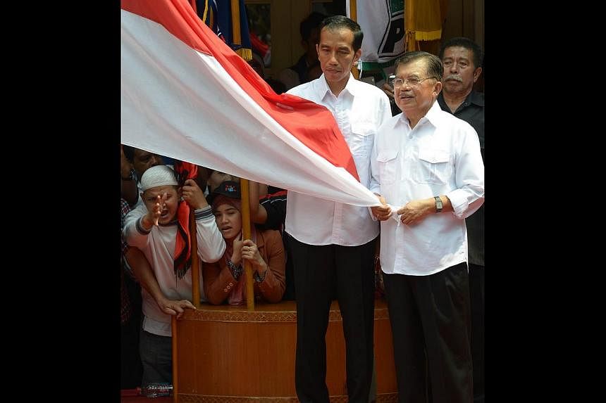 Mr Joko (left) and his running mate Mr Kalla holding Indonesia's national flag during a declaration as presidential and vice-presidential candidates in Jakarta on Monday last week. The next vice-president will be a seasoned politician with much more 
