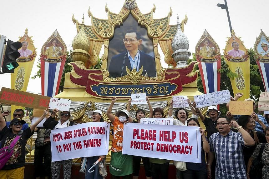 Thai protesters shout slogans and hold placards beneath a portrait of King Bhumibol Adulyadej during a rally against the military junta at Victory Monument in Bangkok, Thailand, on 26 May 2014. -- PHOTO: EPA