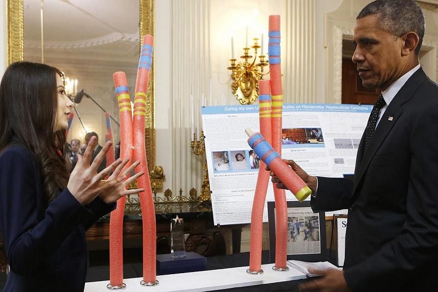 US President Barack Obama (right) looks at the Cancer Research project of Elena Simon (left), New York, NY, during the 2014 White House Science Fair at the White House, Washington DC, USA, on May 27, 2014. The Science Fair features winners of a broad