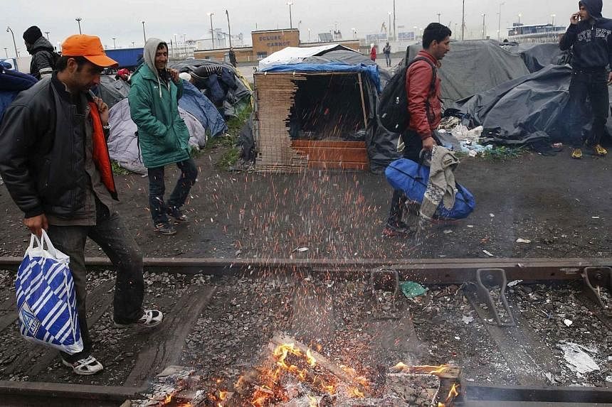 Immigrants leave their makeshift shelter as French police evacuate them from an improvised camp in Calais, northern France on May 28, 2014.&nbsp;French police on Wednesday, May 28, 2014, expelled around 550 people from makeshift camps in the northern