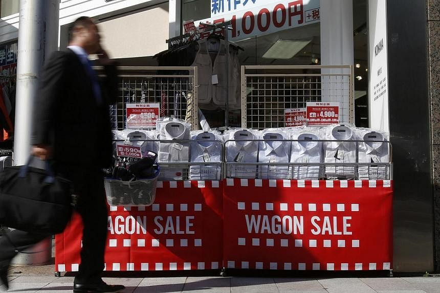 A man walks past shirts on sale outside a store in Tokyo, in this April 7, 2014 file picture. Bank of Japan board member Sayuri Shirai said on Thursday it will take more than two years to achieve the central bank's 2 per cent inflation target, stress