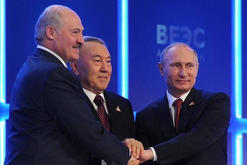 (From right) Russian President Vladimir Putin shakes hands with his Kazakh counterpart Nursultan Nazarbayev and Belarussian counterpart Alexander Lukashenko during a regular meeting of the Supreme Eurasian Economic Council in Astana on May 29, 2014. 