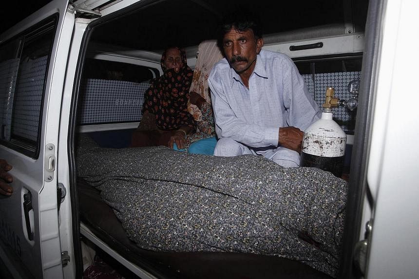 Mohammad Iqbal sits next to his wife Farzana's body, who was killed by family members, in an ambulance outside of a morgue in Lahore on May 27, 2014. -- PHOTO: REUTERS