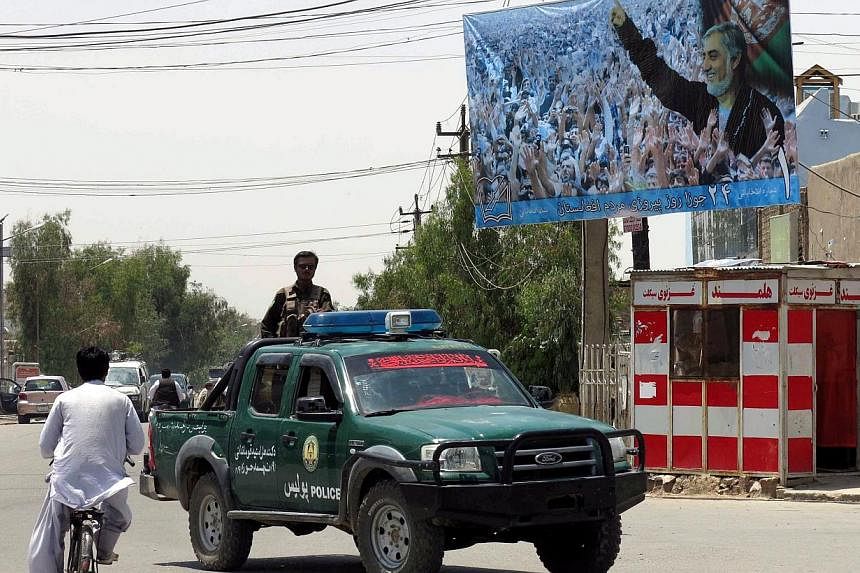 An Afghan police vehicle passes by electoral billboards of presidential candidate Abdullah Abdulah in Kandahar, Afghanistan, 29 May 2014. -- PHOTO: EPA