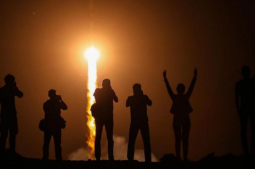 Spectators watch as the Soyuz TMA-13M rocket is launched with Expedition 40 Soyuz Commander Maxim Suraev, of the Russian Federal Space Agency, Roscosmos, Flight Engineer Alexander Gerst, of the European Space Agency, ESA, and Flight Engineer Reid Wis
