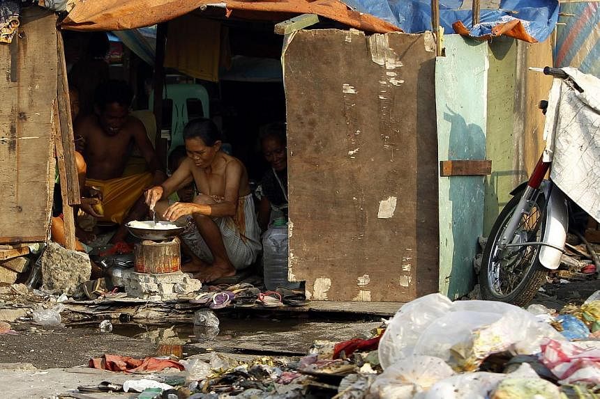 Filipino informal settlers prepare food inside a makeshift home in a slum area of Manila, Philippines on May 28, 2014.&nbsp;A brutal run of natural disasters late last year took their toll on the Philippine economy, slicing growth to 5.7 per cent in 