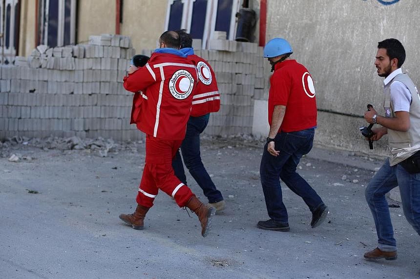 Red Crescent staff run for cover after Syria's air force hit the town of Douma, northeast of Damascus, where they were distributing aid parcels along with a UN team on May 24, 2014. -- PHOTO:AFP
