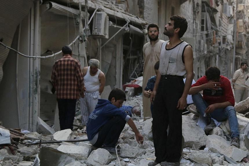 People react among debris of damaged buildings along a street at a site hit by what activists said was a barrel bomb dropped by forces loyal to Syria's President Bashar al-Assad in Aleppo's Bustan al-Qasr neighborhood on May 28, 2014. -- PHOTO: REUTE