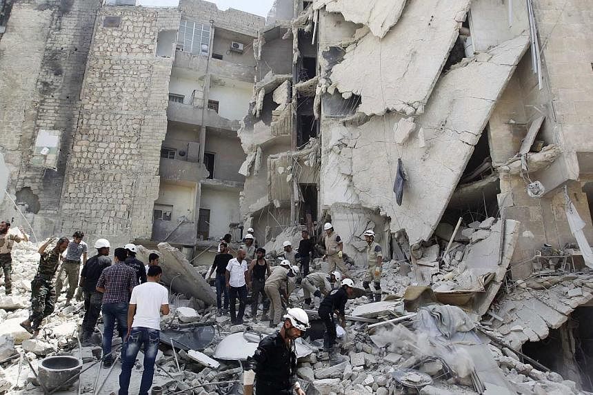 Civil Defence members, rebel fighters and civilians search for survivors at a site hit by what activists said was a barrel bomb dropped by forces loyal to Syria's President Bashar al-Assad in al-Qarlaq neighbourhood of Aleppo on May 29, 2014. -- PHOT