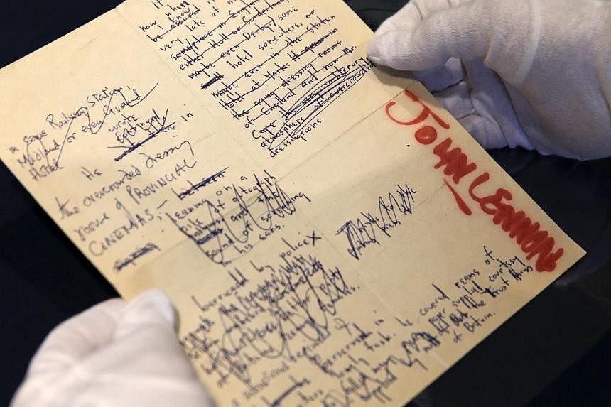A Sotheby's employee handles a typescript signed by John Lennon during the press preview of a collection of Lennon's original drawings and manuscripts from 1964-65 at Sotheby's in New York on May 29, 2014. -- PHOTO: REUTERS