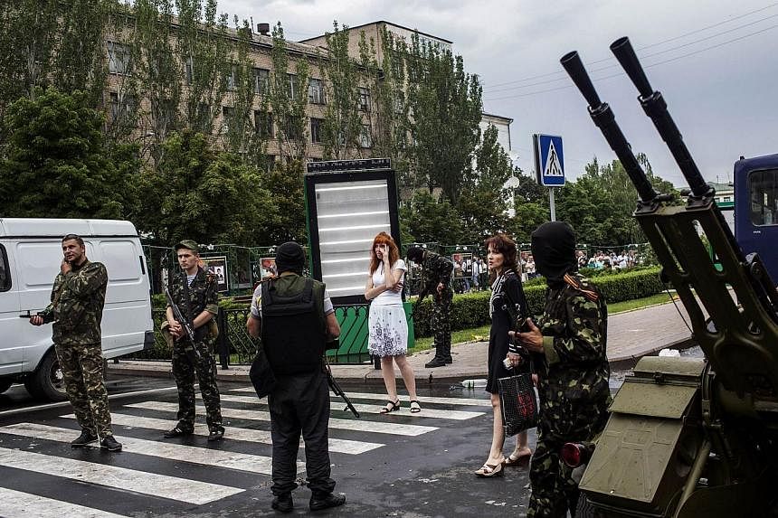 Pro-Russian fighters stand in a street, outside the Donbas building in central Donetsk, on May 29, 2014. Pro-Russian rebels downed a Ukrainian helicopter on May 29, killing 12 soldiers including a general and undermining president-elect Petro Poroshe