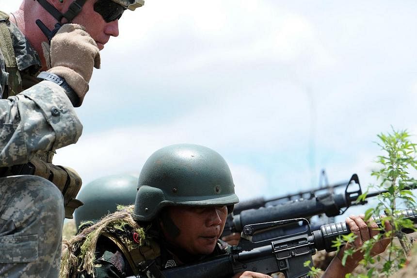 A Philippine soldier (R) fires his weapon while a US soldier (L) supervises during a live fire exercise at a Philippine army training camp in Fort Magsaysay, in Nueva Ecija province north of Manila on May 10, 2014. Philippine&nbsp;lawmaker Carlos Isa